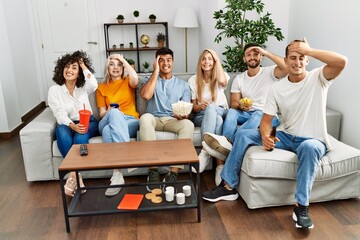 Sticker - Group of people eating snack sitting on the sofa at home stressed and frustrated with hand on head, surprised and angry face