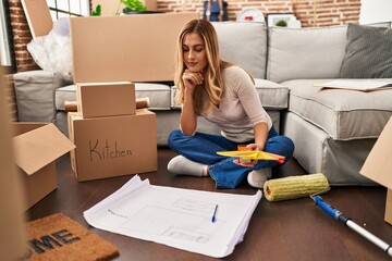 Sticker - Young blonde woman sittng on the floor choosing paint color at new home