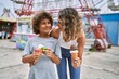 Mother and son smiling confident eating ice cream at theme park