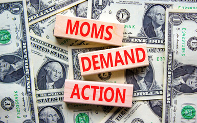 Moms demand action symbol. Concept words Moms demand action on wooden blocks on a beautiful background from dollar bills. Business, finacial and Moms demand action concept.