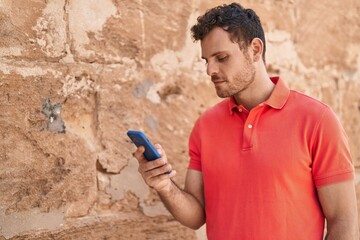 Poster - Young hispanic man using smartphone at street