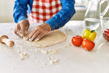 Senior man keading dough with hands at kitchen