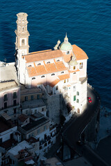 Wall Mural - View from above, stunning aerial view of a beautiful old church with a slender bell tower situated on a cliff just beside the coast line. Atrani, Amalfi Coast, Salerno, Italy.