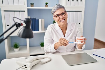 Sticker - Middle age woman wearing dentist uniform teaching to wash tooth at clinic