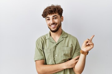 Poster - Young arab doctor man standing over isolated background with a big smile on face, pointing with hand finger to the side looking at the camera.