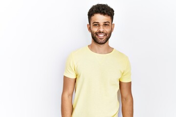 Poster - Arab young man standing over isolated background looking away to side with smile on face, natural expression. laughing confident.