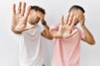 © Krakenimages.com - Young gay couple standing over isolated background covering eyes with hands and doing stop gesture with sad and fear expression. embarrassed and negative concept.