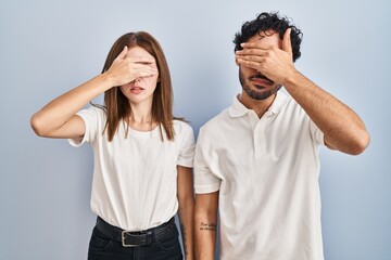 Poster - Young couple wearing casual clothes standing together covering eyes with hand, looking serious and sad. sightless, hiding and rejection concept