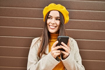 Wall Mural - Young hispanic girl smiling happy using smartphone at the city.