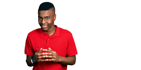 Young african american man wearing casual red t shirt hands together and fingers crossed smiling relaxed and cheerful. success and optimistic