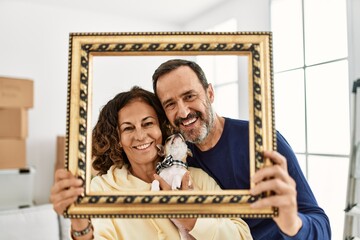 Sticker - Middle age hispanic family smiling happy holding empty frame at new home.