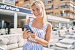 © Krakenimages.com - Young blonde girl smiling happy using smartphone at the city.