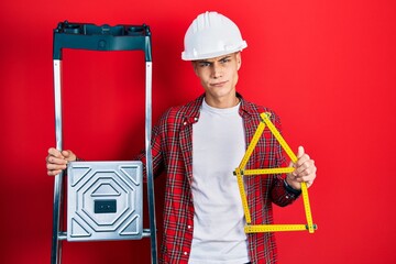 Wall Mural - Young hispanic man wearing handyman uniform holding construction stairs and house project skeptic and nervous, frowning upset because of problem. negative person.