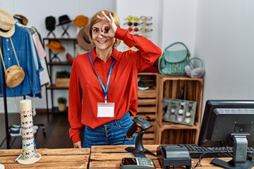 Sticker - Middle age blonde woman working working as manager at retail boutique doing ok gesture with hand smiling, eye looking through fingers with happy face.