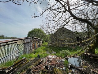 Wall Mural - Large metal shed, with scrap metal and farm buildings nearby, with a bird of prey in the sky near, Stainforth, UK