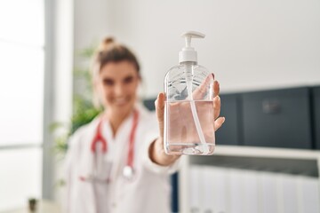 Sticker - Young blonde woman wearing doctor uniform holding sanitizer gel hands at clinic