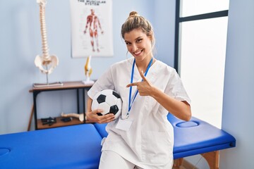 Canvas Print - Young woman working at football therapy clinic smiling happy pointing with hand and finger