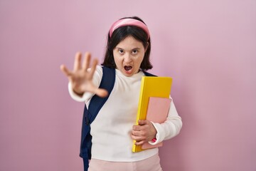 Sticker - Woman with down syndrome wearing student backpack and holding books doing stop gesture with hands palms, angry and frustration expression