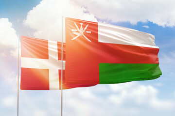 Sunny blue sky and flags of oman and denmark