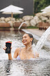 Young beautiful woman in bikini drinking cocktail getting hydrotherapy in outdoor pool
