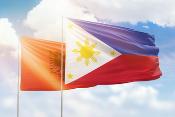 Sunny blue sky and flags of philippines and albania