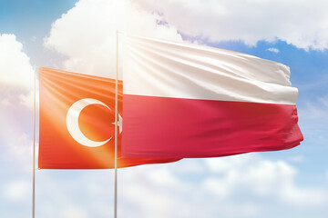 Sunny blue sky and flags of poland and turkey