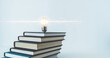 © Koto Amatsukami - Glowing lightbulb or bright lamp with book or textbook. Skill improvement for student or businessperson. Studying and training course online at home. Business success idea, education learning concept