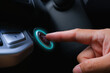© BLKstudio - The driver palm as it presses the electric car engine start stop button with a green light illuminated