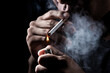 close up of a man smok a cigarette on black background