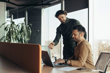 Canvas Print - Experienced colleague explaining to young coworker business project strategy at contemporary office, copy space