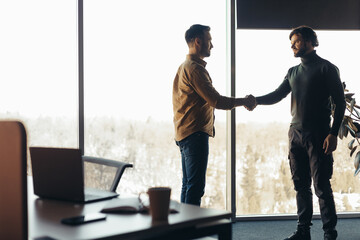 Sticker - Two serious businessmen shaking hands, making deal or agreement at contemporary office, empty space