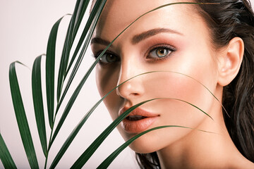Wall Mural - young beautiful woman with green leaves near face. skin care beauty treatments concept. closeup girl