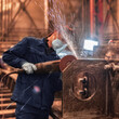 A factory worker grinding metal. Locksmith work.