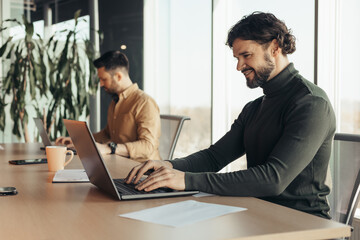 Sticker - Happy company employee using laptop, working next to male colleague at open space office