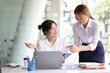 © Wasan - Business woman in office holding documents working, consulting with colleagues about project work planning.