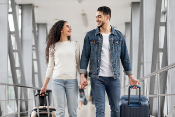 Wall Mural - Portrait Of Romantic Middle Eastern Spouses Walking With Suitcases At Airport Hall