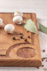 Wall Mural - square wooden cutting board of dark color with edging. mushrooms and spices on a white background. mockup with copy space for text, side view, close-up