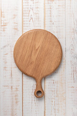 Wall Mural - round cutting board with a handle on a white wooden table. mockup of a food background with copy space, top view