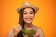 Smiling woman with bare shoulders wearing Mexican hat eating tomato on fork, big smile with teeth, isolated portrait, girl face portrait with natural no retouching skin.