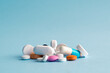 Heap of of colorful pills tablets and capsules on blue background with copy space for text.