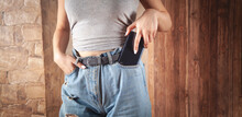 Woman Putting Smartphone In Pocket Of Jeans.