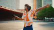 Close-up of cheerful young African American man wearing shirt listening to music in headphones and dancing on urban city background. Lifestyle concept