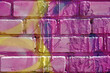 Textured background of a brick street wall painted in bright purple colors with yellow streaks and streaks of paint.Copyspace.