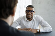 © fizkes - African businessman negotiates take part in business meeting in office. Two multi ethnic men talking during appointment, vacancy applicant pass job interview. Human resources, staffing, hiring concept