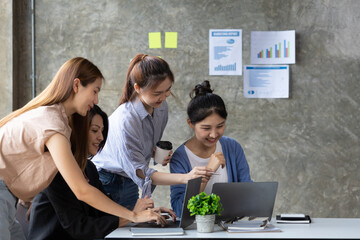 Wall Mural - A group of young Asian business women stand and talk. Jointly open a startup company and a business plan management plan to grow the business and be profitable by the concept of the new generation.