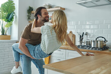 Young Loving Couple Embracing And Having Fun At The Domestic Kitchen