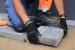 Układanie kostki brukowej na przygotowanym terenie z piasku i cementu. Brukarstwo.

