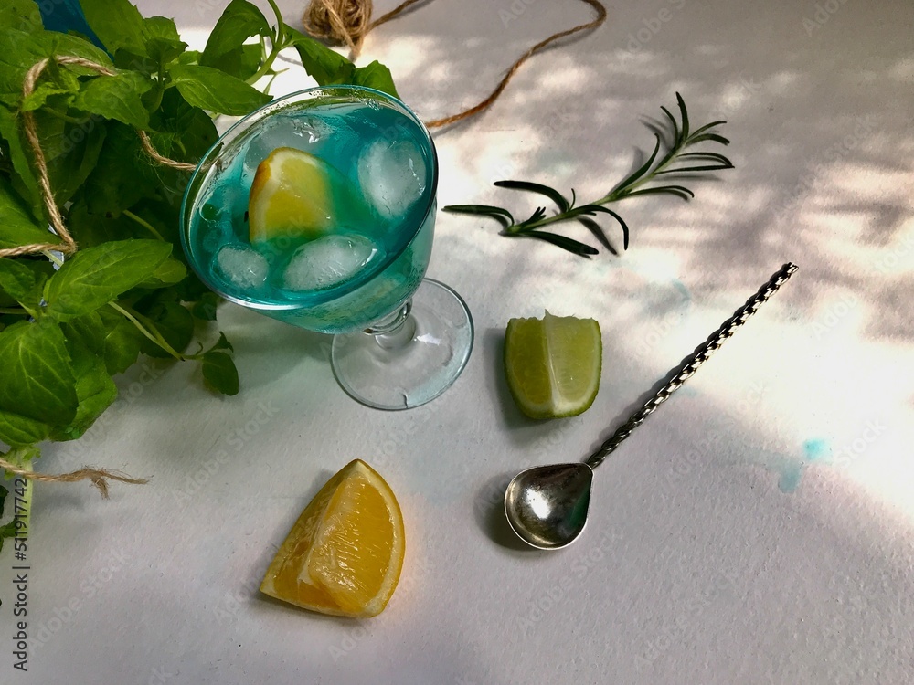 Blue cold drink in a glass with ice cubes on white desk with blue ...