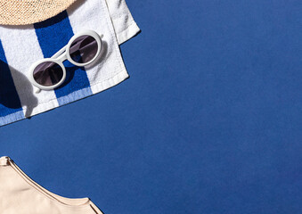 Canvas Print - Summer vacation beach concept frame with retro sunglasses, striped towel and straw hat on the blue background. Copy space	