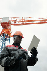Poster - Modern experienced builder or foreman looking at screen of digital tablet during network or online communication with colleague or subordinate